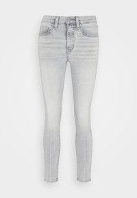 Jeans skinny gris claro hechos de denim, con un clásico diseño de cinco bolsillos, cierre de cremallera con botón y un ligero desvanecimiento en las piernas.