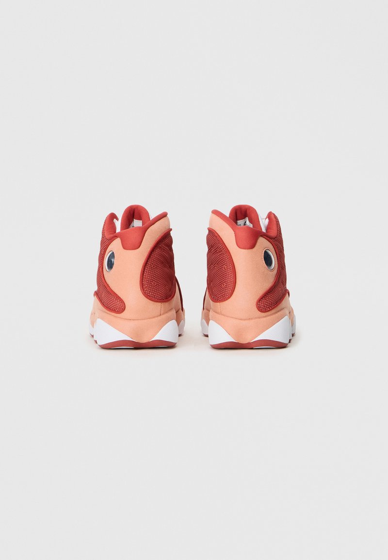 Sneaker alte in rete corallo e rossa con colletto imbottito, dettagli degli occhi prominenti e suola in gomma bianca. Superfici texturizzate e lisce.