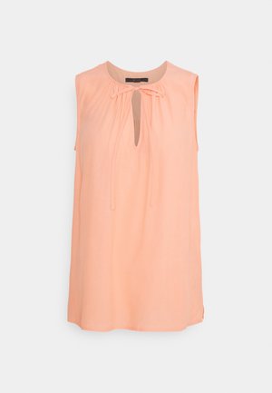 Damska bluzka bez rękawów w kolorze brzoskwiniowym z okrągłym dekoltem, wycięciem typu keyhole oraz wiązaniem z przodu, o luźnym kroju i lekkim materiale.