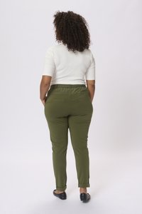 Pantalons de yoga verts avec un design ajusté, une taille élastique et deux poches arrière. Associés à un haut blanc ajusté et des ballerines noires.