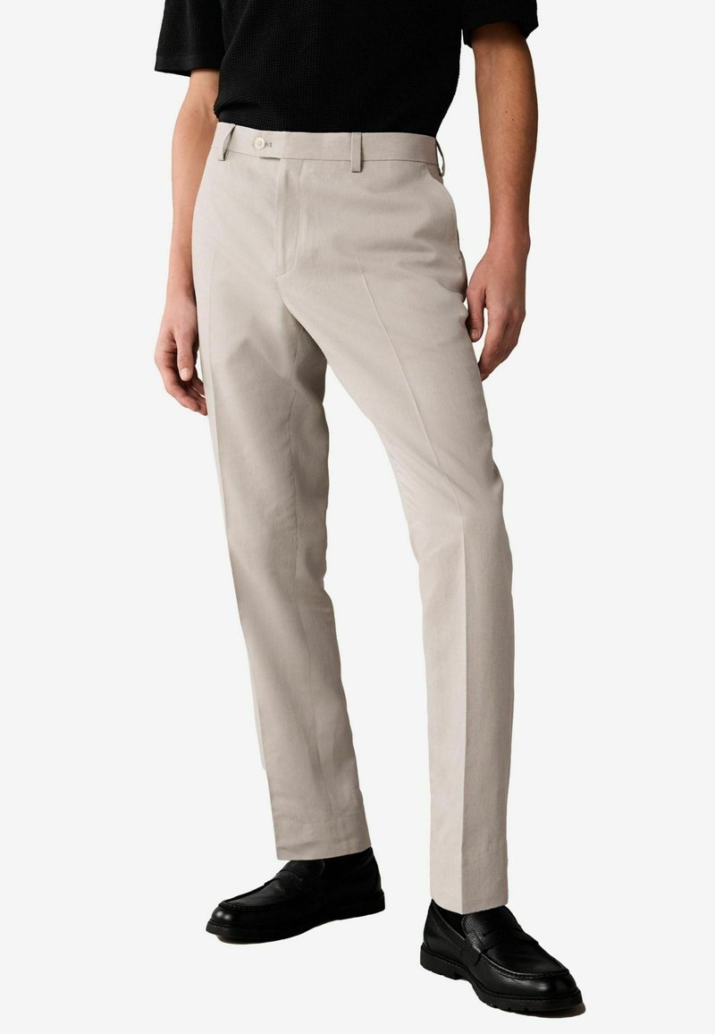 Beige tailored trousers with a smooth texture, featuring a straight leg design, side pockets, and a single-button front closure.