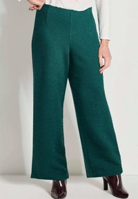 Teal wijde broek gemaakt van textuurstof, met een hoge taille en zijzakken, gecombineerd met donkere hooghakken.