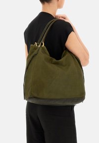 Borsa a tracolla in pelle verde con un design morbido, dotata di hardware dorato e dettagli intrecciati. Texture opaca, forma oversize.