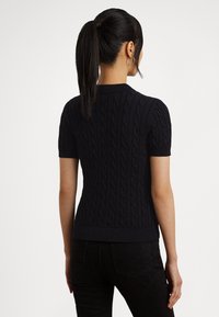 Čierny krátky rukáv pletený sveter so vzorom kábla, rebrovanými okrajmi a priliehavým strihom, zobrazený zozadu.