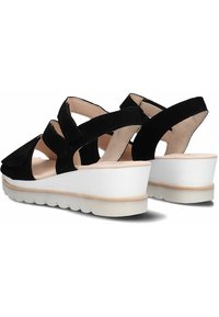 Zwarte suede wedge sandalen met meerdere gekruiste banden, witte plateauzool en een gestructureerde lichtbruine onderkant voor grip.