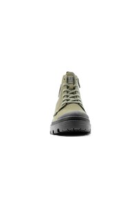 Zapatilla alta de lona verde con suela de goma negra, punta redonda y costuras en contraste. Cuenta con un diseño de cordones y ojales reforzados.