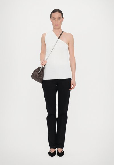 Λευκή ασυμμετρία μπλούζα, μαύρο εφαρμοστό παντελόνι, συνδυασμένο με μια σκούρα καφέ υφασμάτινη τσάντα και μαύρες μυτερές εσπαντρίλλες.