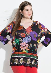 Schwarze Tunika mit bunten Blumen- und Blattmustern, V-Ausschnitt und drei Viertelärmeln, akzentuiert mit einem dekorativen Saum.
