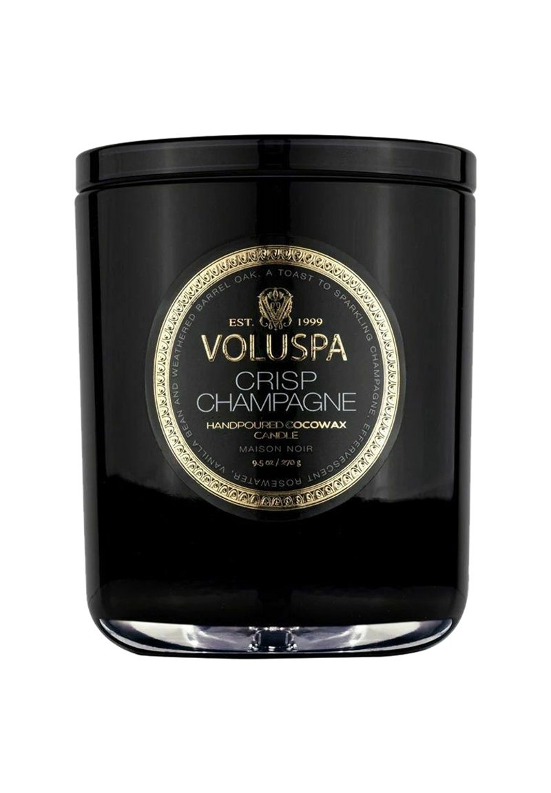 Musta lasikynttiläpurkki, jossa on kultainen etiketti, jossa lukee "VOLUSPA CRISP CHAMPAGNE." Käsinvalettua kookosvahaa, 9,5 unssia. Pyöreä muotoilu, kiiltävä viimeistely.