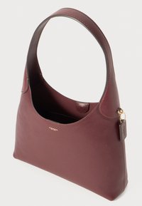 Burgundy leather shoulder bag with a smooth texture, a rounded body, a short handle, and a small tag featuring the brand name.