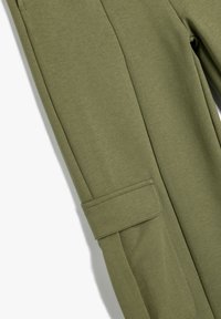 Oliven grønne sweatpants i blødt stof, der har sidelommer, en glat tekstur og en skræddersyet pasform med manchetter i benene.