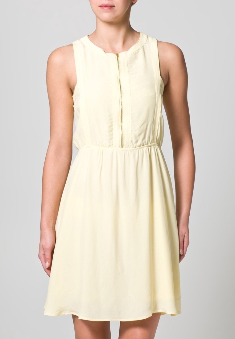 Vestido sin mangas de color amarillo claro con escote redondo, cremallera en el frontal, cintura elástica y tela suave y fluida.