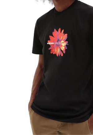 Sort T-shirt med et farverigt blomstermotiv i pink og orange. Teksten lyder "VANS OFF THE WALL." Blødt bomuldsmateriale med korte ærmer.