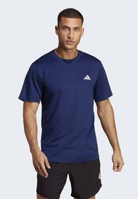 Marinblå sport-t-shirt i lätt tyg, korta ärmar, rund halsringning, med en liten vit logotyp på vänster bröst.