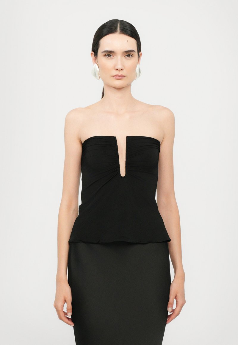 Top negro sin tirantes con un pronunciado escote en V, tela fruncida y un dobladillo de peplum; la textura suave resalta el diseño minimalista.