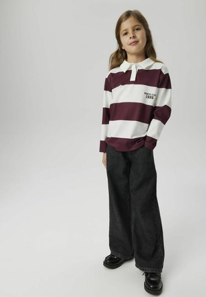 Långärmad maroon- och vitrandig polo med krage, kombinerad med vida mörk denimbyxor och svarta skor.