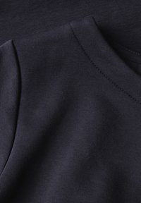 Primer plano de una tela acanalada de un azul marino oscuro con un detallado de costura y una textura suave.