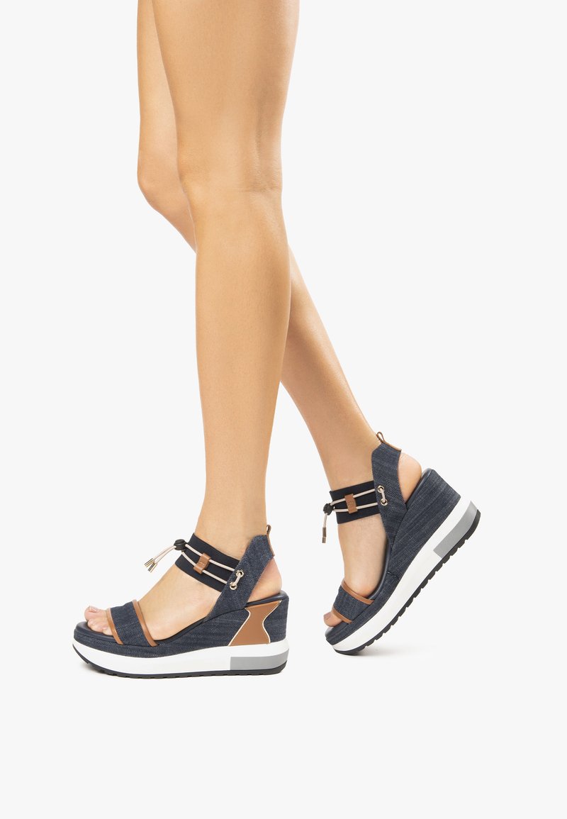 Keilsohlen-Sandalen aus dunkelblauem Stoff mit braunen Akzenten, ausgestattet mit zwei Riemen, offenen Zehen und einer weißen Plattformsohle aus strukturiertem Gummi.