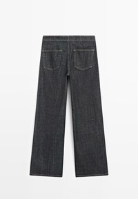 Ciemnoniebieskie dżinsy o szerokich nogawkach z klasycznym paskiem, dwoma tylnymi kieszeniami i widocznym przeszyciem. Gładka tekstura o swobodnym wyglądzie.