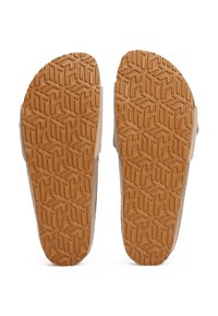 Soli de sandale din cauciuc maro prezintă un design patterned cu forme geometrice și texturi, înconjurate de o parte superioară din material bej.