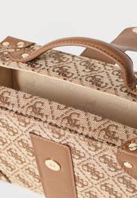 Hnedá vzorovaná kabelka z látky s hladkým koženým uchom, zlatou kovovou výbavou a pevnou štruktúrou so zabezpečeným zapínaním.