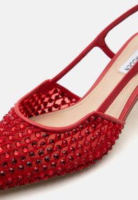 Κόκκινο παπούτσι slingback με διάφανο δίχτυ επάνω μέρος διακοσμημένο με κόκκινες στρας και μπεζ πάτο.