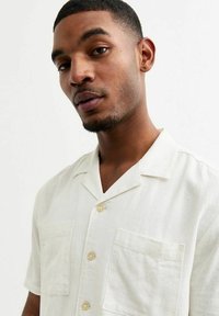 Witte linnen kortekoe shirt met een camp collar, knoopsluiting aan de voorkant en twee opgestikte zakken. Zachte textuur en lichtgewicht ontwerp.