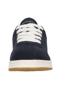 Tennarit tummansinisestä mokasta, joissa on valkoiset nauhat, pyöreä kärki ja valkoinen kumipohja vaaleanruskealla yksityiskohdalla, esittelevät minimalistista muotoilua.