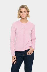 Cardigan rose clair avec un col rond, des manches longues et une fermeture à boutons, ornée de petits boutons ressemblant à des perles. Porté avec un jean en denim foncé.