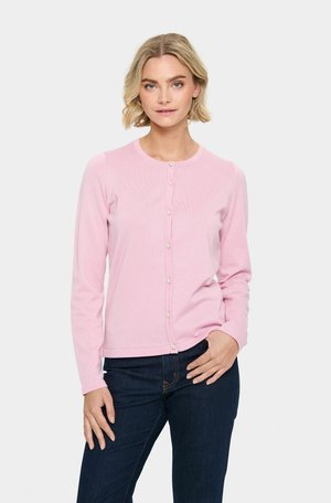 Cardigan rose clair avec un col rond, des manches longues et une fermeture à boutons, ornée de petits boutons ressemblant à des perles. Porté avec un jean en denim foncé.