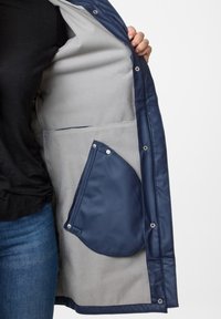 Navy blue padded jacket, featuring a gray fleece lining, snap buttons, and a large front pocket with a smooth texture.