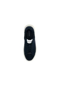 Sneaker in suede nero di Guess con lacci neri, suola bianca e etichetta di branding bianca sulla linguetta, vista dall'alto su sfondo bianco.
