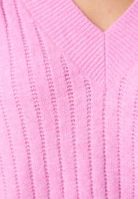 Lichtroze gebreide trui met een V-hals, met verticale ribbeltextuur en subtiele details. Zachte, lichtgewicht stof.