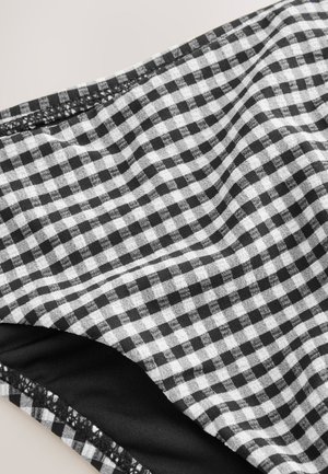 Sort og hvid gingham-stof med en blød tekstur, der har små ternede mønstre. En indre sort lag er synligt langs kanten.