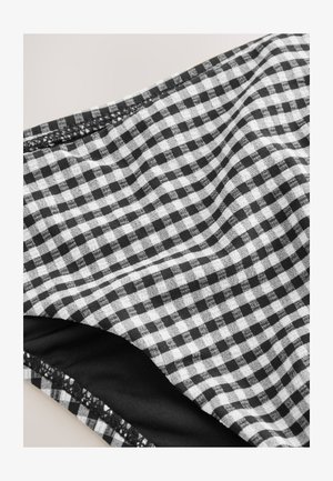 Sort og hvid gingham-stof med en blød tekstur, der har små ternede mønstre. En indre sort lag er synligt langs kanten.