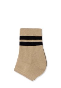 Beige ankelstrømpe med sorte horisontale striber nær toppen, lavet af blødt strikket materiale med en glat tekstur.