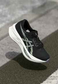 Schwarzer Laufschuh mit einem strukturierten Mesh-Obermaterial, kontrastierender weißer Zwischensohle und lebhaften Akzenten. Verfügt über ein aerodynamisches Design für optimale Leistung.