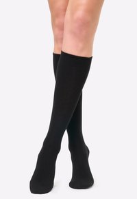 Calcetines negros hasta la rodilla, hechos de un material suave y elástico, con un puño acanalado en la parte superior y sin patrones ni acentos visibles.