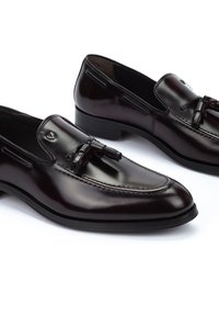 Mocasines de cuero burdeos con un acabado suave, acentos decorativos de borlas y costuras tonales. Tacón bajo con punta redondeada.