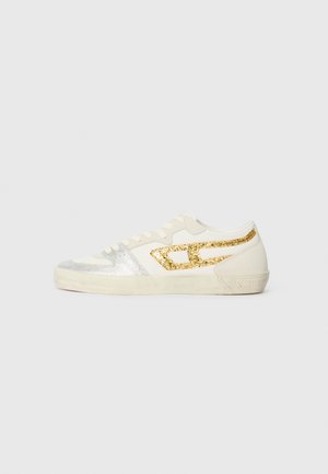 Hvit sneaker med sølv- og gullglitterdetaljer, med lav profil, teksturert stoff og gummisåle. Snøringer og logo synlige.