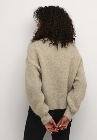 Světlé zelený, volný pletený svetr s žebrovanými manžetami a lemem. Měkká textura, spadená ramena a volný střih, pohled zezadu.