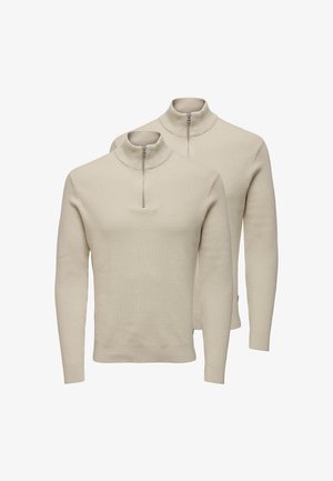 Kaksi vaaleanbeigeä vetoketjukauluksella varustettua neulepuseroa, valmistettu ribbineuloksesta, jossa on pitkät hihat ja istuva siluetti.