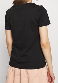 T-shirt nera a maniche corte in morbido misto cotone, presenta un colletto girocollo e una vestibilità slim con una texture liscia e dettagli di cucitura discreti.