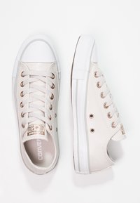 Beiga läder låga sneakers med vit gummikappa och sula, med ögla och snörning i guldton samt en logotagg på tungan.