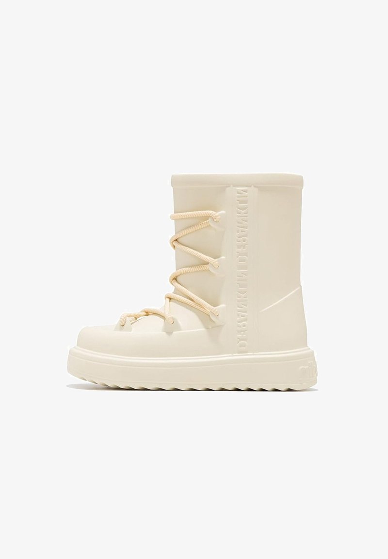 Bota de goma blanca con cordones frontales y cuerdas beige. Detalle de logo texturizado en el lateral y suela acanalada para tracción.