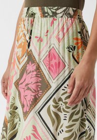 Maxirock aus einem gemusterten Stoff mit pinken, orangefarbenen und grünen Blumen- und geometrischen Designs; elastischer Bund mit einem Kordelzug.