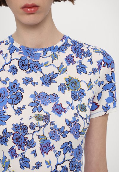 Short-sleeve top in lightweight fabric, white base with blue and green floral print, crew neckline, and visible stitching details.