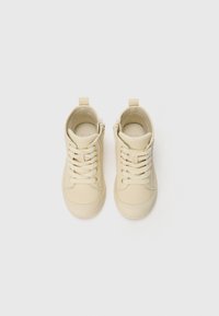 Zapatillas altas beige hechas de material suave, con diseño de cordones, cremalleras laterales y puntera redondeada con sutilezas en los detalles de costura.