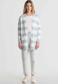 Dryžuotas cardigan šviesiai mėlynos ir baltos spalvos, pagamintas iš minkštos medžiagos, su atvira priekiu, ilgomis rankovėmis ir dviem priekiniais kišenėmis.