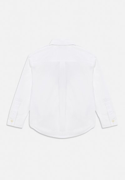 Chemise blanche à manches longues vue de dos, avec un pli central au dos et des poignets boutonnés.